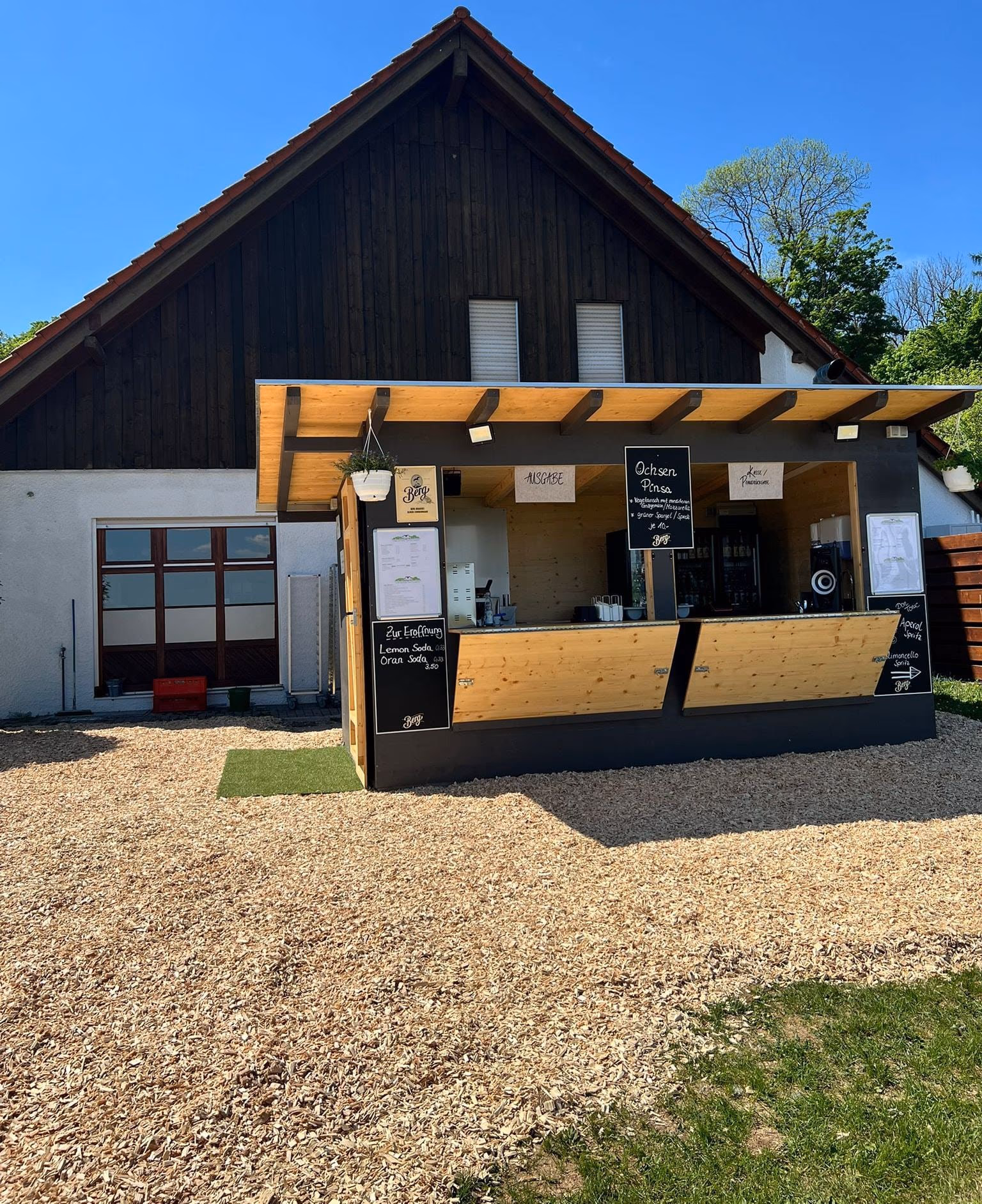 Ausschank aus hellem Holz im Biergarten mit Kreidetafeln